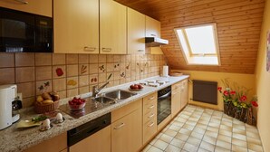 Une cuisine avec des meubles de rangement en bois, un four à micro-ondes, un évier et une fenêtre.
