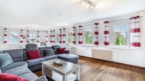 Una sala de estar moderna con un sofá seccional gris, una mesa de centro y cortinas rojas y blancas.