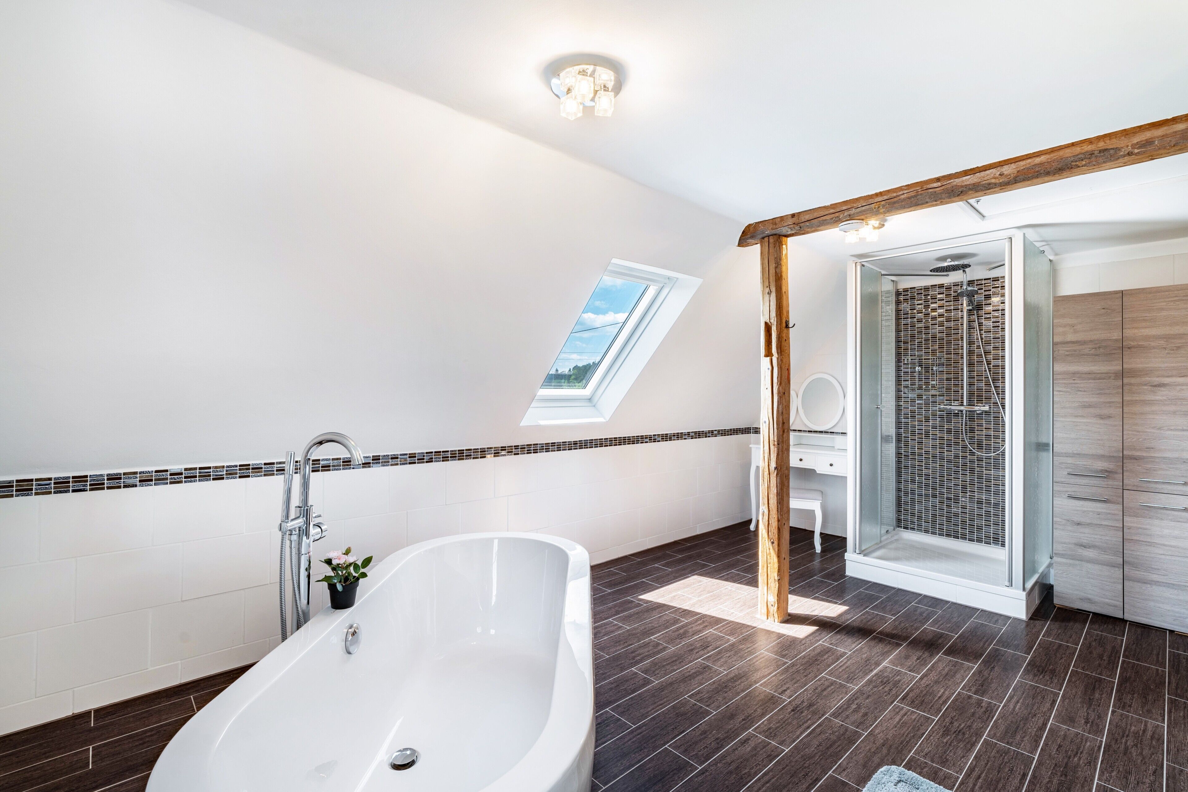 Ein modernes Badezimmer mit freistehender Badewanne, einer Duschkabine aus Glas und einem Oberlicht.