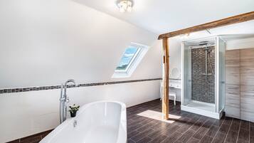 Ein modernes Badezimmer mit freistehender Badewanne, einer Duschkabine aus Glas und einem Oberlicht.