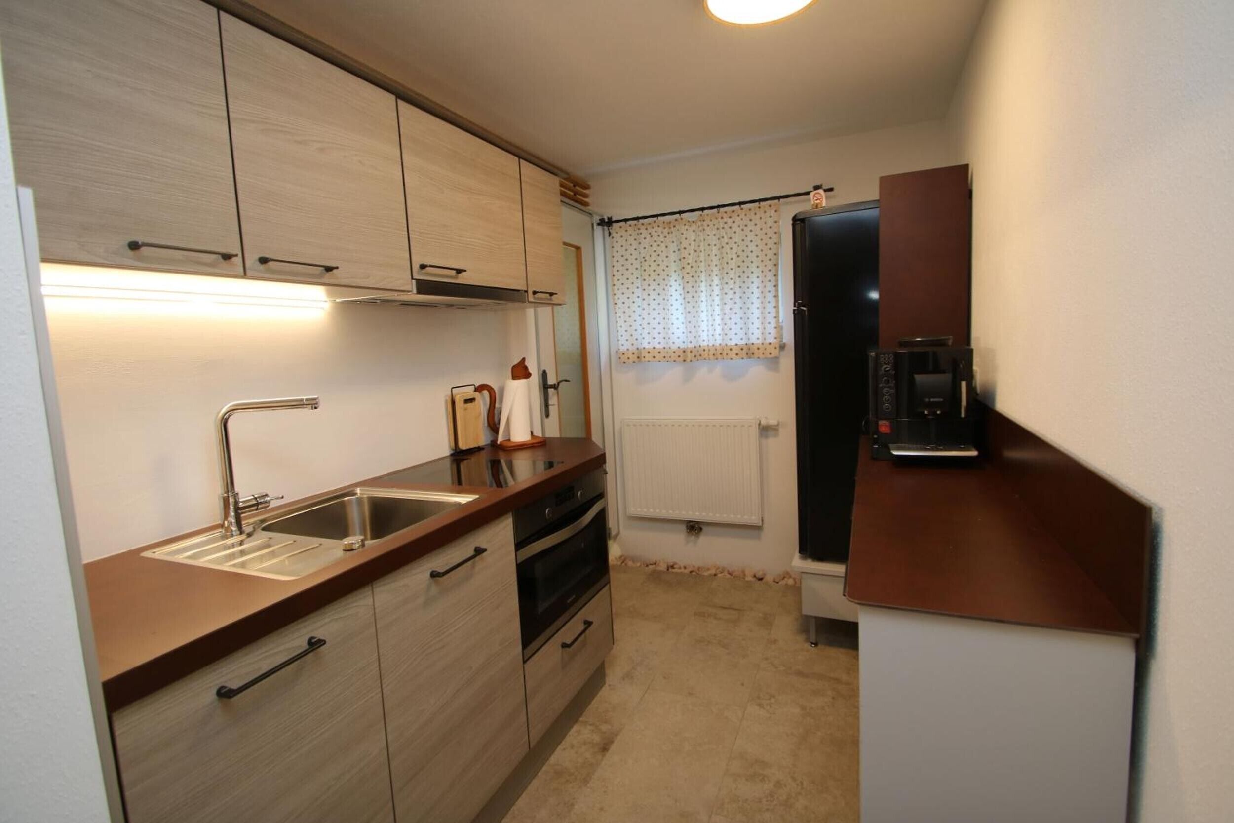 A compact kitchen with a sink, oven, and a refrigerator.