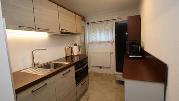A compact kitchen with a sink, oven, and a refrigerator.