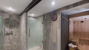 Un baño moderno con cabina de ducha de vidrio, sauna de madera y un reloj visible en la pared.