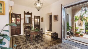 Un comedor con suelo estampado, una araña de cristal y vistas al jardín exterior a través de un vano abierto.