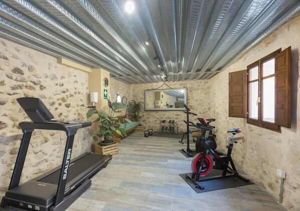 A home gym with a treadmill, stationary bike, and weights.