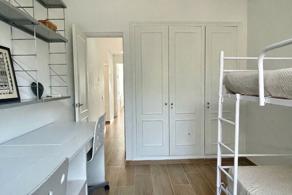 Een kamer met stapelbedden, een bureau en een garderobe.