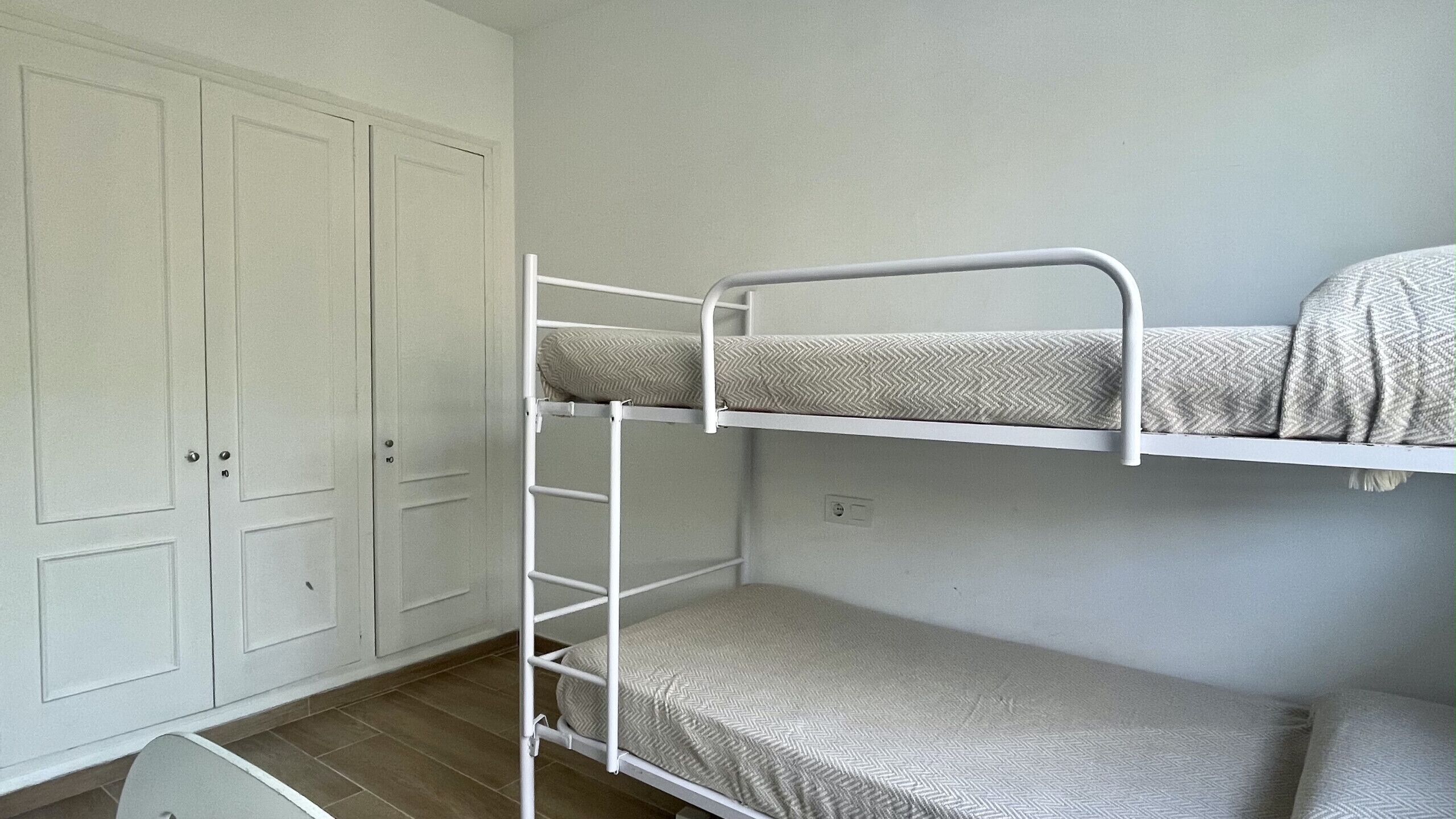Una cama litera con escalera, un armario y una puerta.