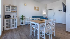 Eine moderne Küche mit weißen Schränken, einem Holztisch und weißen Stühlen.