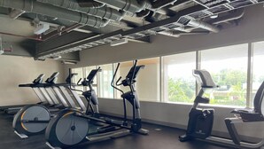Une salle de sport équipée de vélos d’appartement, de tapis de course et d’un appareil elliptique.