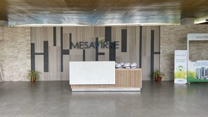 Un comptoir d’accueil avec une enseigne « MESAVIRRE », un espace d’accueil en bois et un panneau indiquant « PAS DE MASQUE, PAS D’ENTRÉE ».