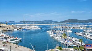 A marina with numerous boats docked, a clear blue sky, and a distant coastline with hills. - Sea view terrace close to the beach of Lido di San Giovanni in Alghero (Alghero)