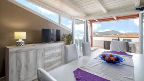 A modern dining area with a white table, purple placemats, and a fruit bowl. - Sea view terrace close to the beach of Lido di San Giovanni in Alghero (Alghero)