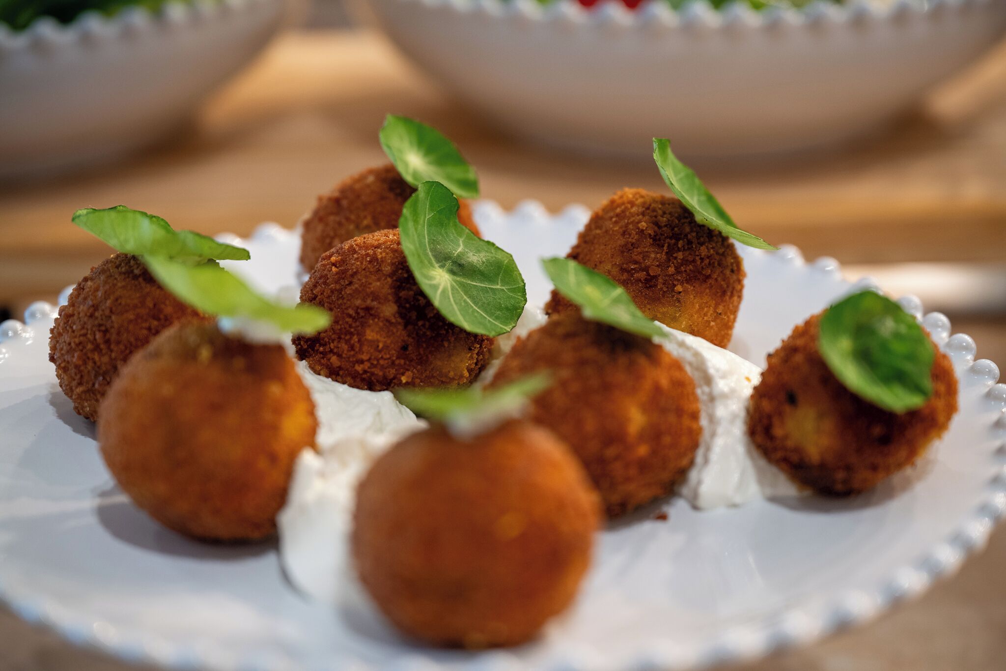 A plate of breaded and fried balls garnished with green leaves.