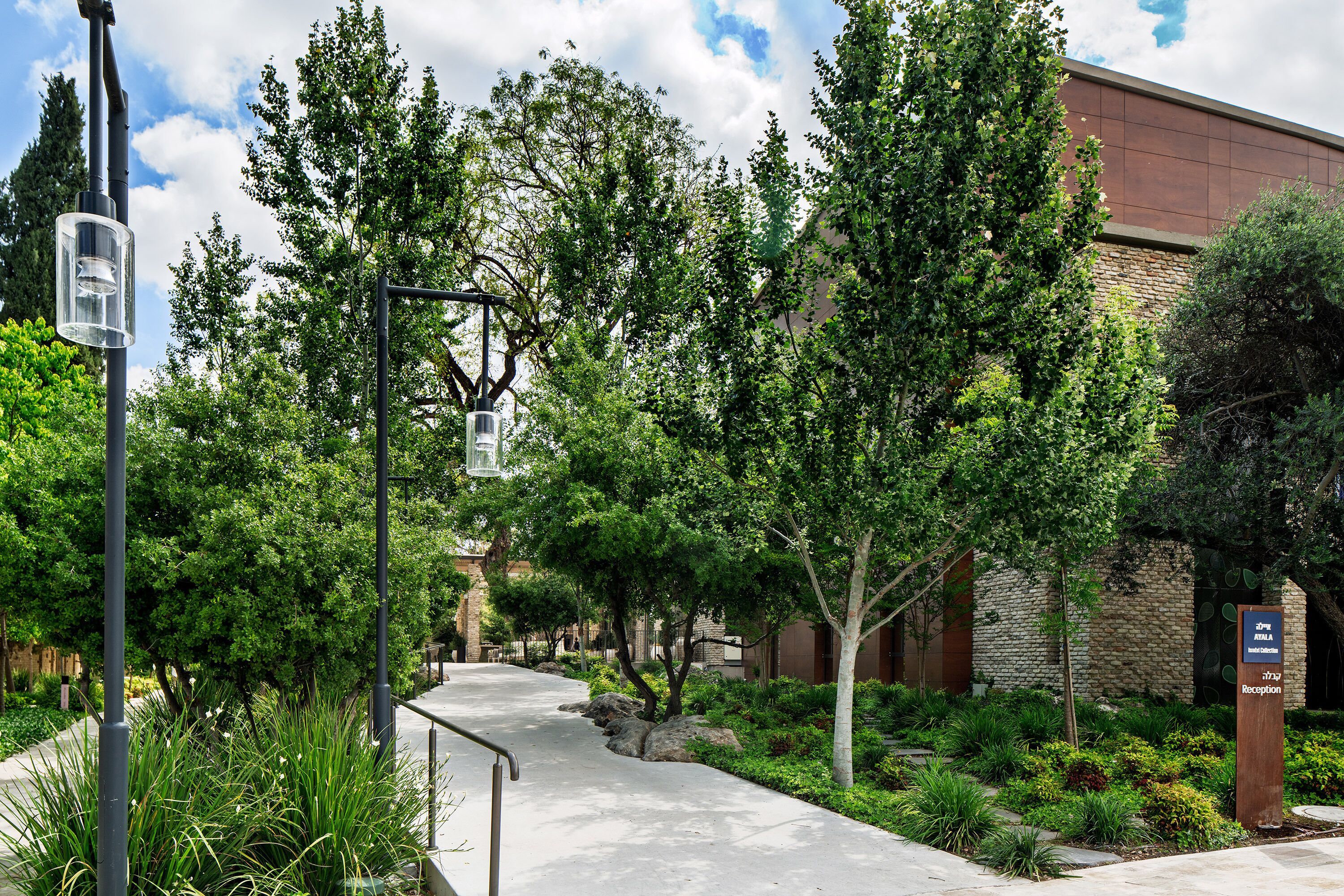 A pathway leading to a building with a reception area, surrounded by greenery and trees.