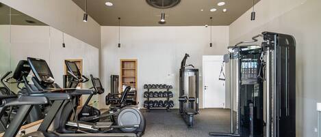 A gym with treadmills, dumbbells, and weight machines.