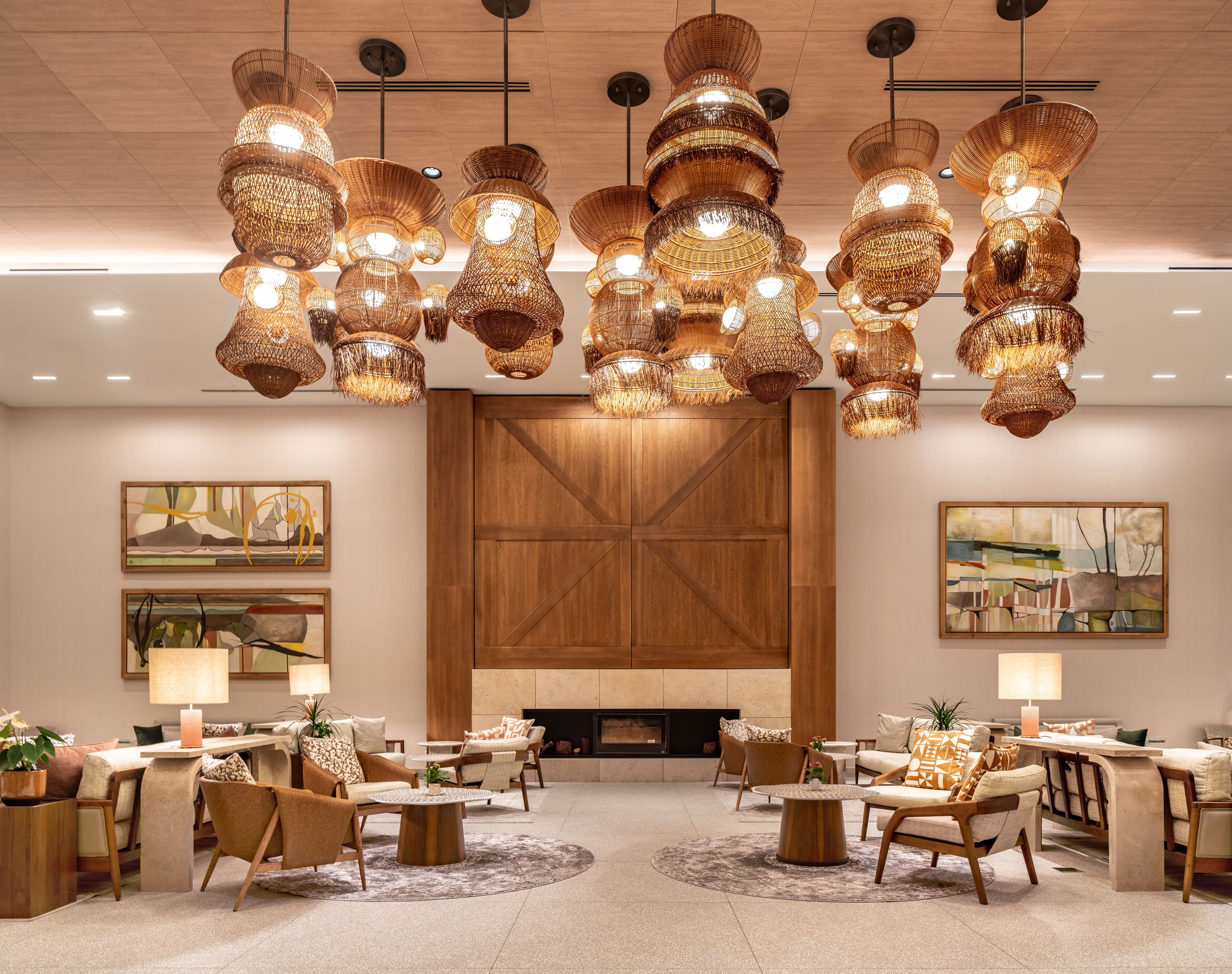 A modern lounge area with multiple seating arrangements, a fireplace, and decorative lighting fixtures.