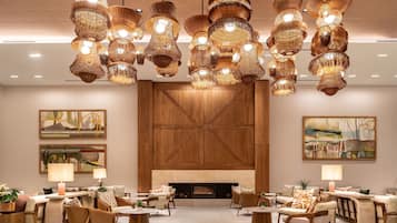 A modern lounge area with multiple seating arrangements, a fireplace, and decorative lighting fixtures.