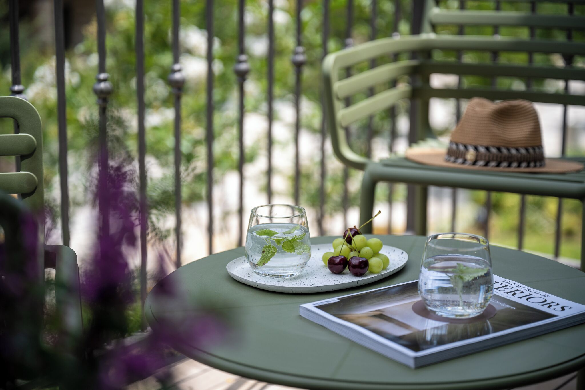 A table with a glass of water, a plate of grapes, and a magazine titled "The World of Interiors."