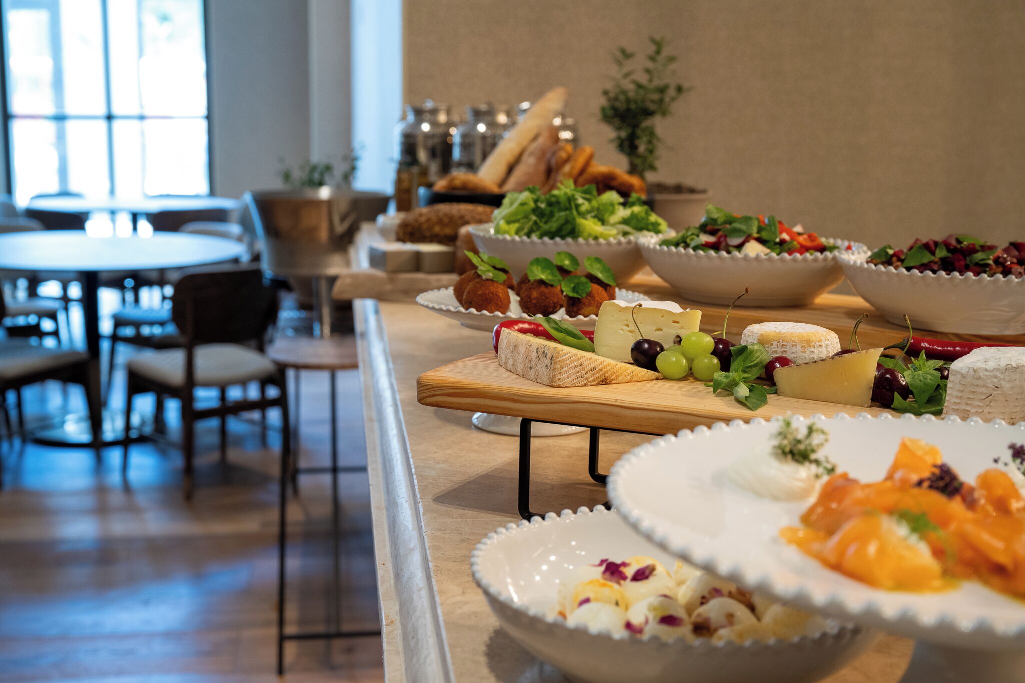 A buffet table with various dishes, including cheese, fruits, and salads.