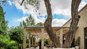 An outdoor patio area with a pergola, seating, and a large tree. - Ayala by Isrotel Collection (HaGalil HaElyon)