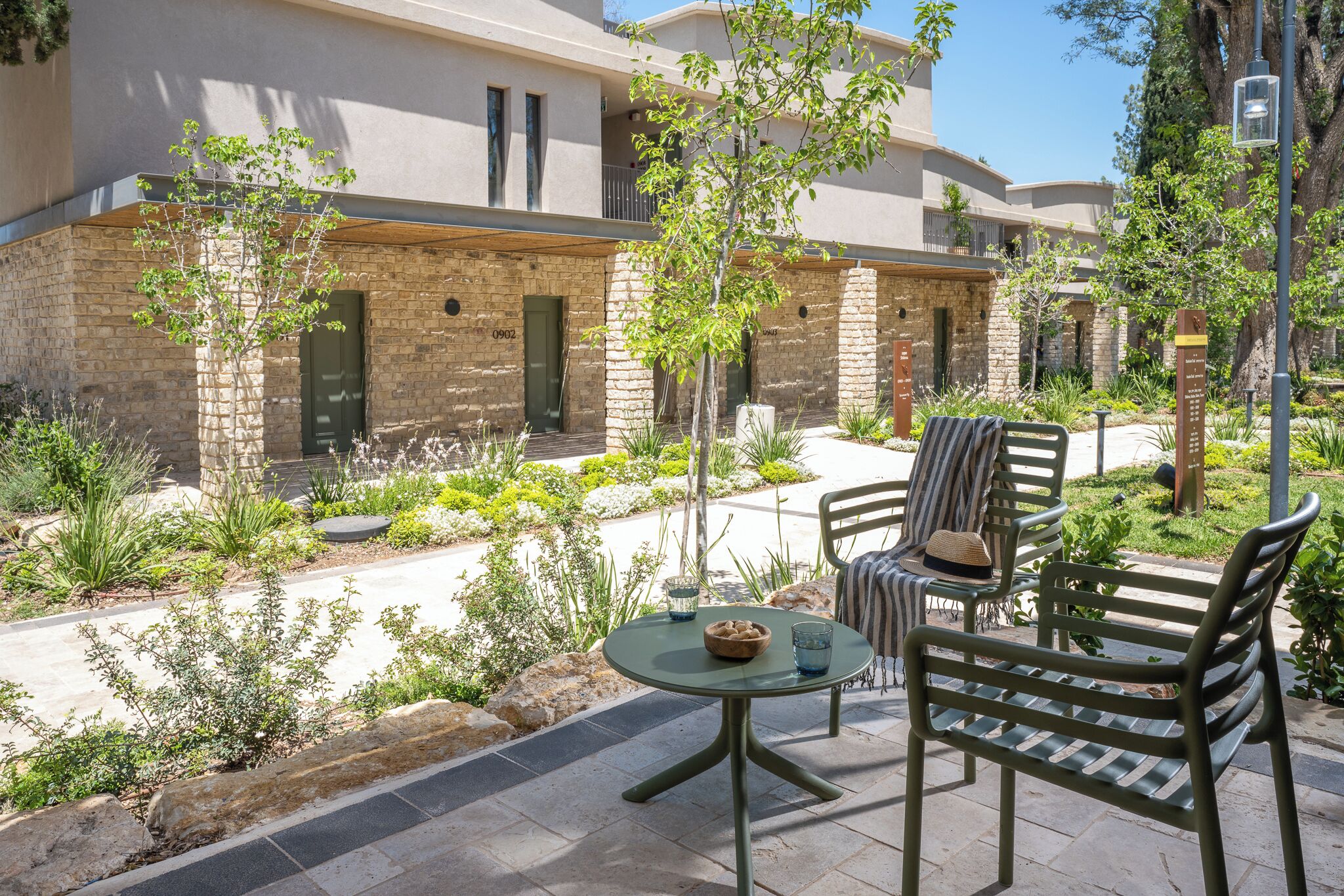 A courtyard with outdoor seating, a stone wall, and a building with multiple windows and balconies.