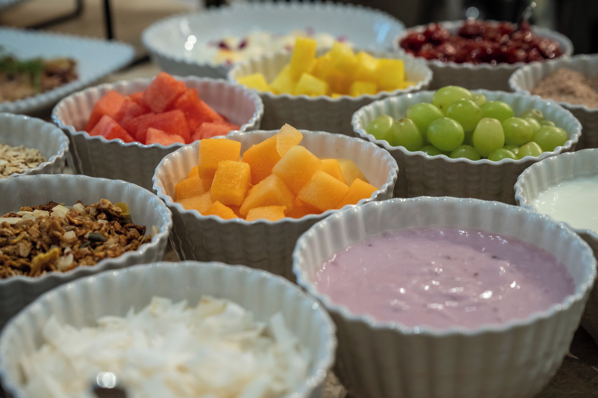 A variety of food items in bowls, including fruits and a pink dessert.