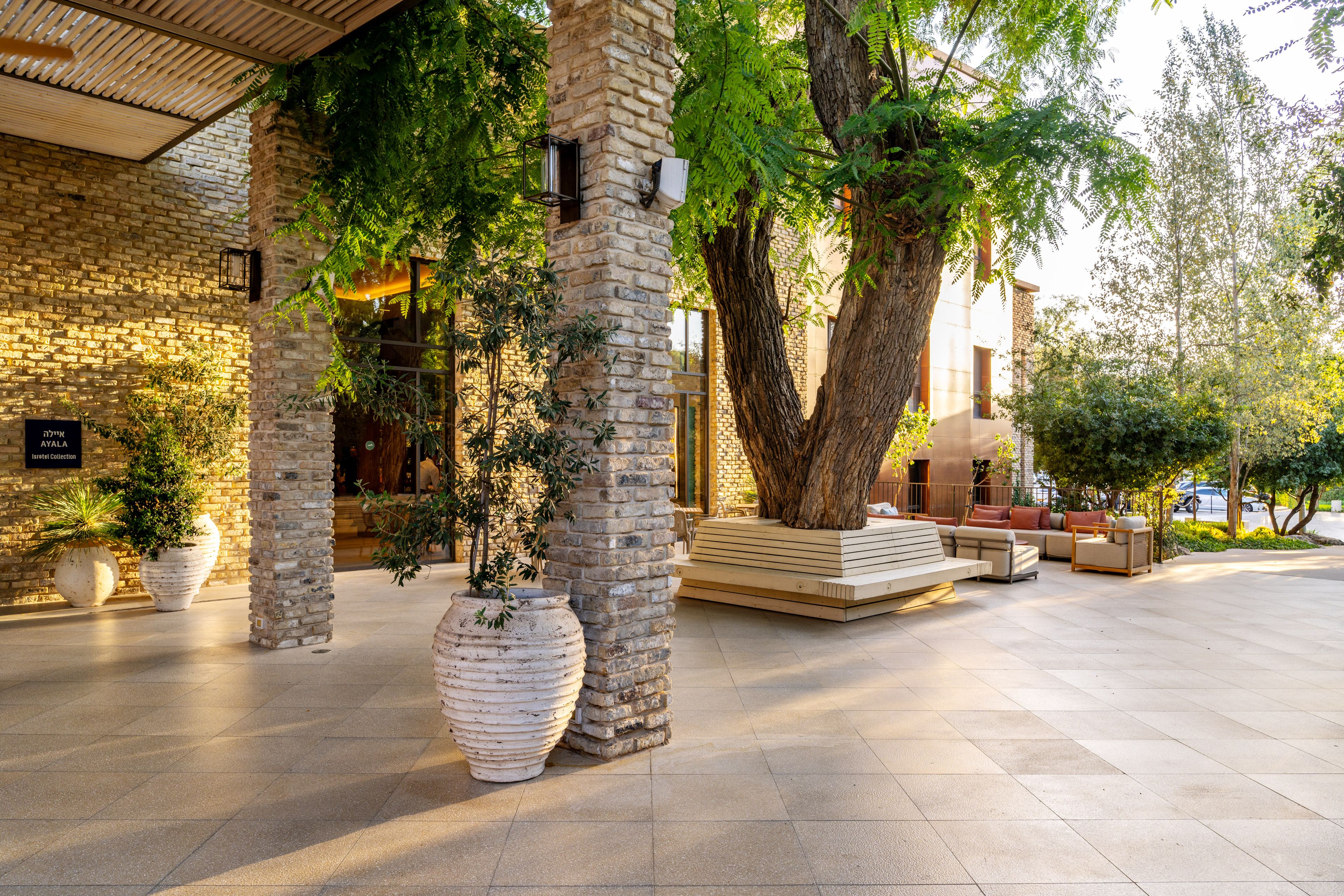 A courtyard with stone pillars, large potted plants, and outdoor seating.