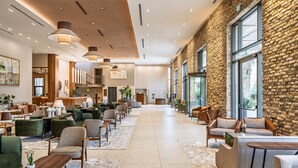 A spacious lobby with a high ceiling, stone wall, and large windows. - Ayala by Isrotel Collection (HaGalil HaElyon)