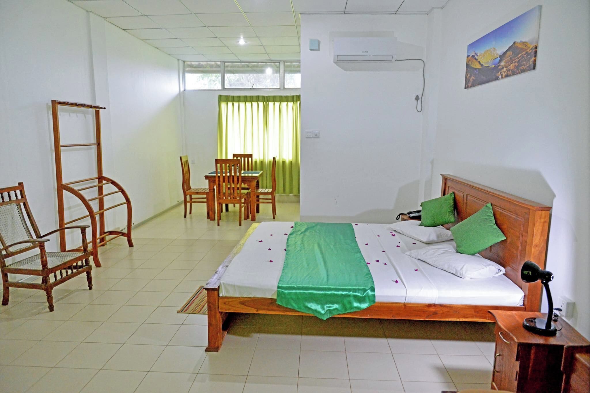 A hotel room with a bed, a desk, a chair, a wardrobe, and a window with curtains.