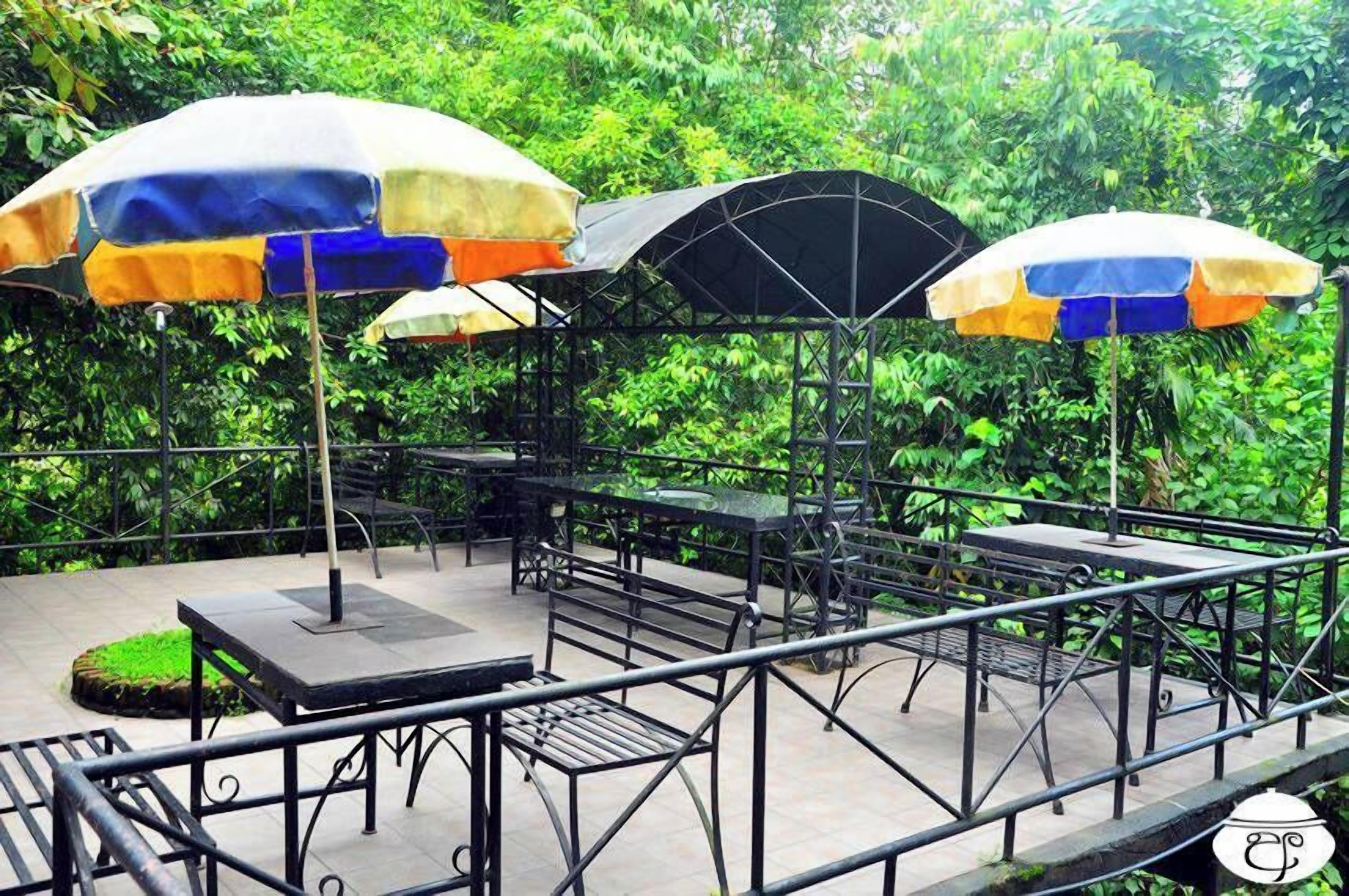 Un patio al aire libre con mesas y sillas, algunas bajo sombrillas.