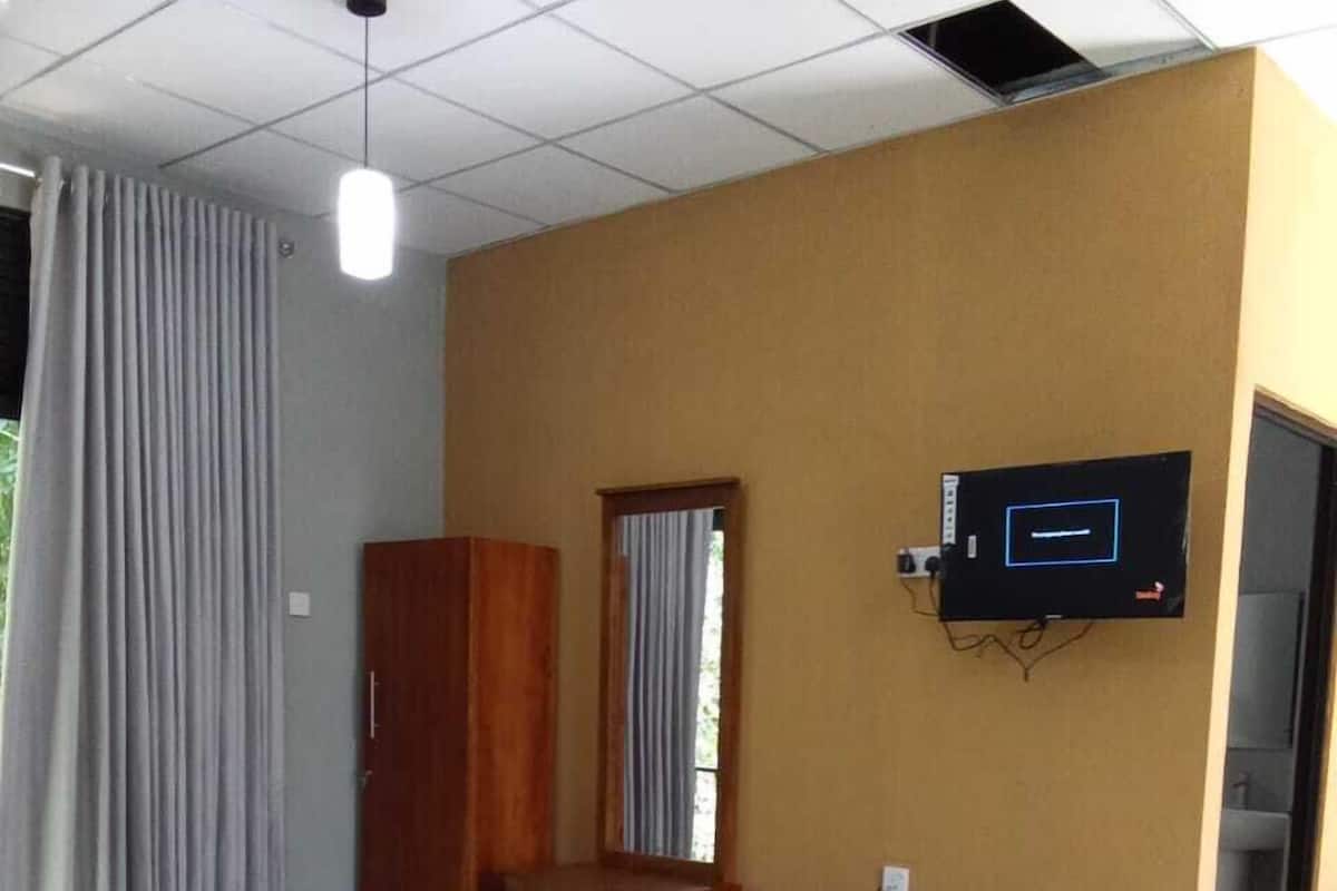 Une chambre d’hôtel équipée d’un lit, d’un bureau, d’une chaise, d’un téléviseur fixé au mur et d’une fenêtre avec des rideaux.