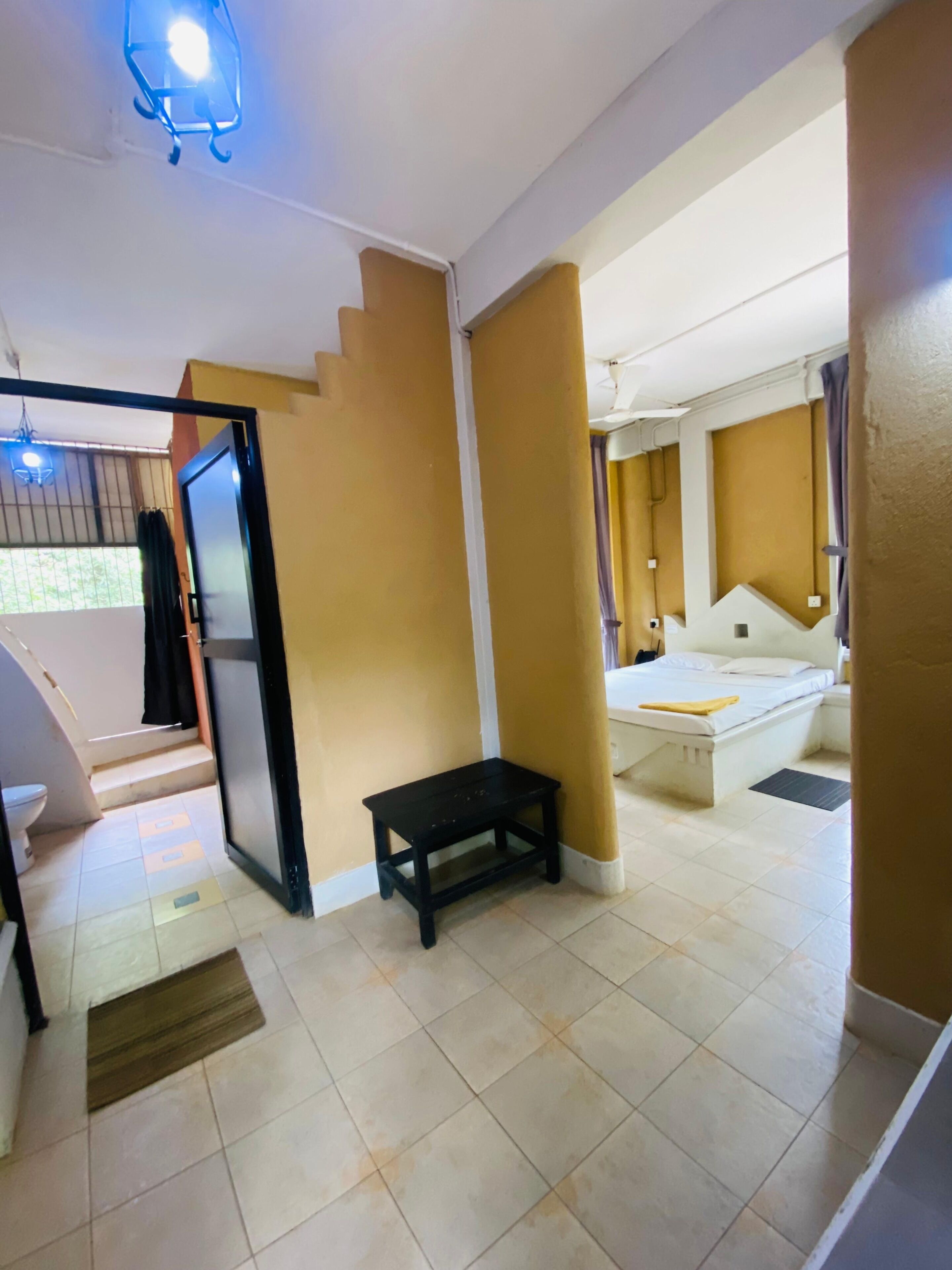 A room with a bed, a small table, and a bathroom with a toilet and sink.