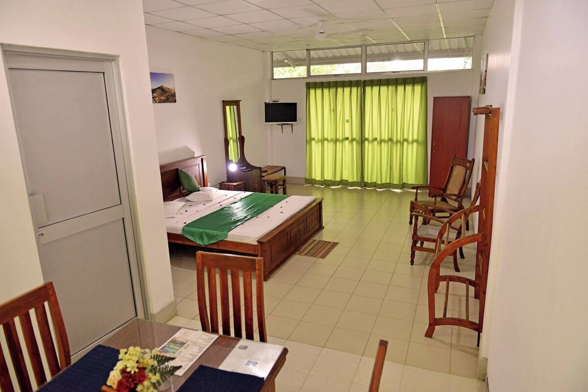 Une chambre d’hôtel équipée d’un lit, d’un bureau, d’une chaise, d’une télévision et d’une fenêtre avec des rideaux.