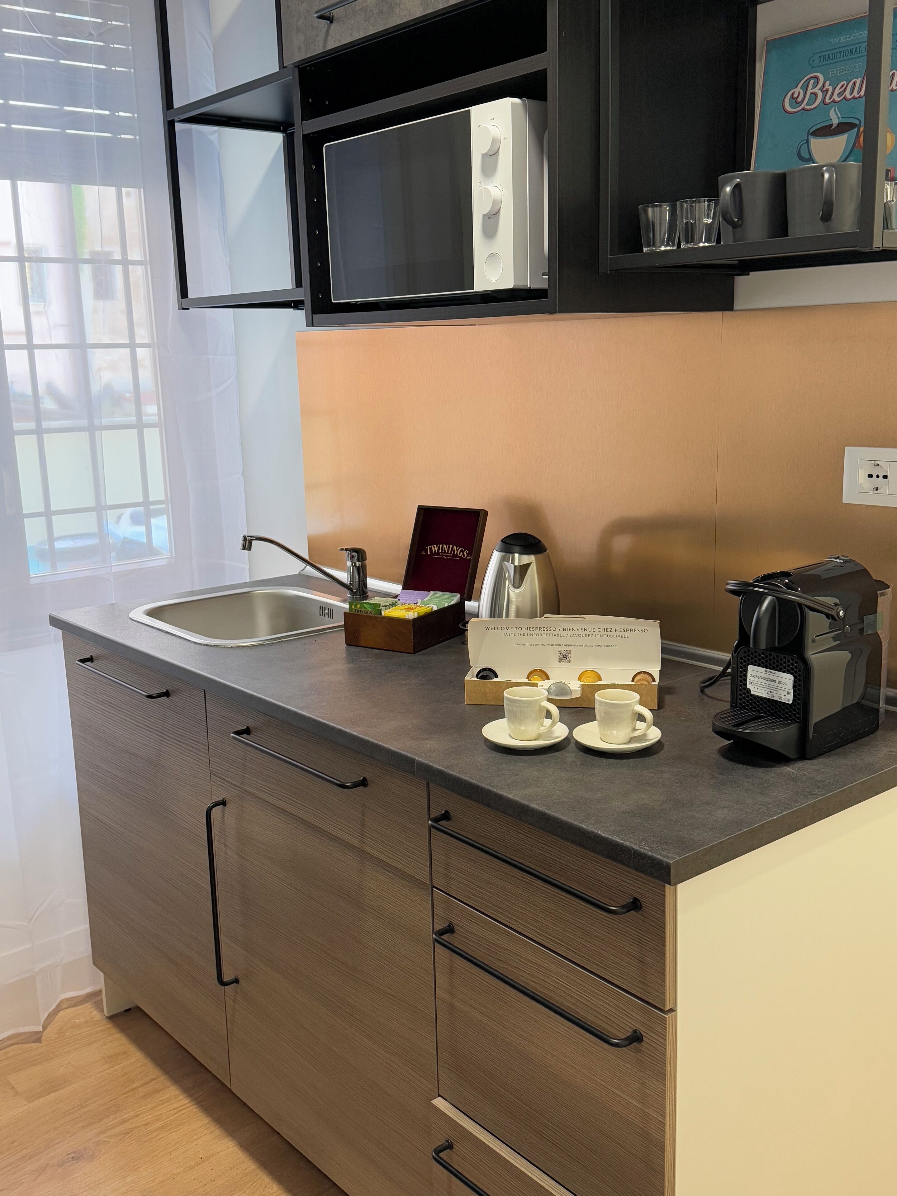 Una cocina moderna con un fregadero, una máquina de café y una caja de té Twinings.