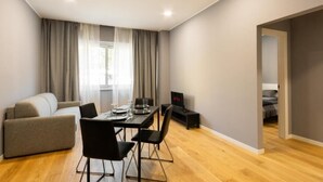 A modern living room with a sofa, dining table, chairs, and a TV.