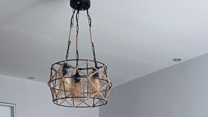 Un comedor moderno con una mesa de madera para cuatro personas, sillas grises y una lámpara colgante.