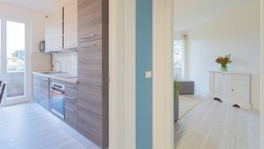 Eine moderne Küche mit Backofen, Mikrowelle und Spüle. Eine Schiebetür führt zu einem Balkon.