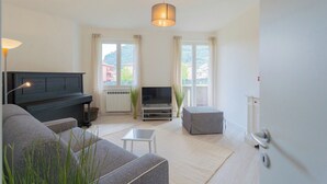 Ein modernes Wohnzimmer mit einem Klavier, einem Flachbildfernseher und einer Couch.