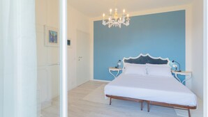 Ein Schlafzimmer mit einem großen Bett, einer Chandelüster, Nachttischen und einer Tür.