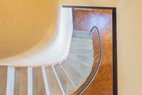 A spiral staircase with a metal railing, carpeted steps, and a wooden floor at the bottom. - Antiche Mura by Rent all Como (Como)