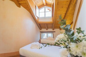 A bedroom with a wooden ceiling, a window, and a bed with neatly folded towels. - Antiche Mura by Rent all Como (Como)