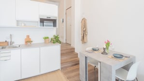 Eine moderne Küche mit weißen Schränken, einer Holz Arbeitsplatte und einem Essbereich mit Tisch und Stühlen.
