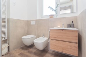 Une salle de bain moderne avec un bidet, un meuble-lavabo en bois et un miroir au-dessus du lavabo.