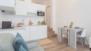 Eine moderne Küche mit weißen Schränken, einer Mikrowelle und einem Essbereich mit Tisch und Stühlen.