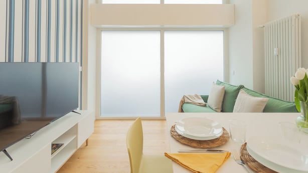 A modern living room with a flat-screen TV, a dining table set for two, and a green sofa with cushions. - A Step From the Lake Apartment by Rent all Como (Como)