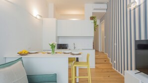 A modern kitchen with white cabinets, a central island with bar stools, and a TV on the right. - A Step From the Lake Apartment by Rent all Como (Como)