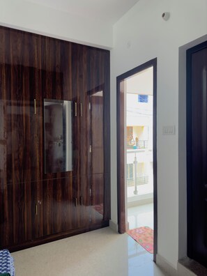 Quarto com guarda-roupa de madeira escura, porta que dá para uma varanda exterior e chão ladrilhado.