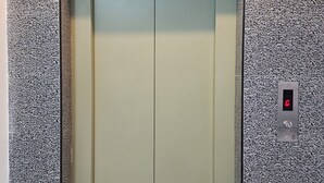 An elevator with a textured wall and a control panel with a red light. - Sishya Service Apartment - Chennai OMR  (Chennai)