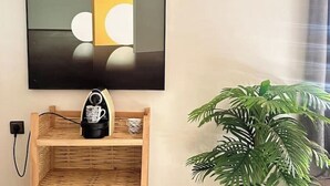 A wall-mounted television, a coffee maker on a wooden shelf, and a potted plant.