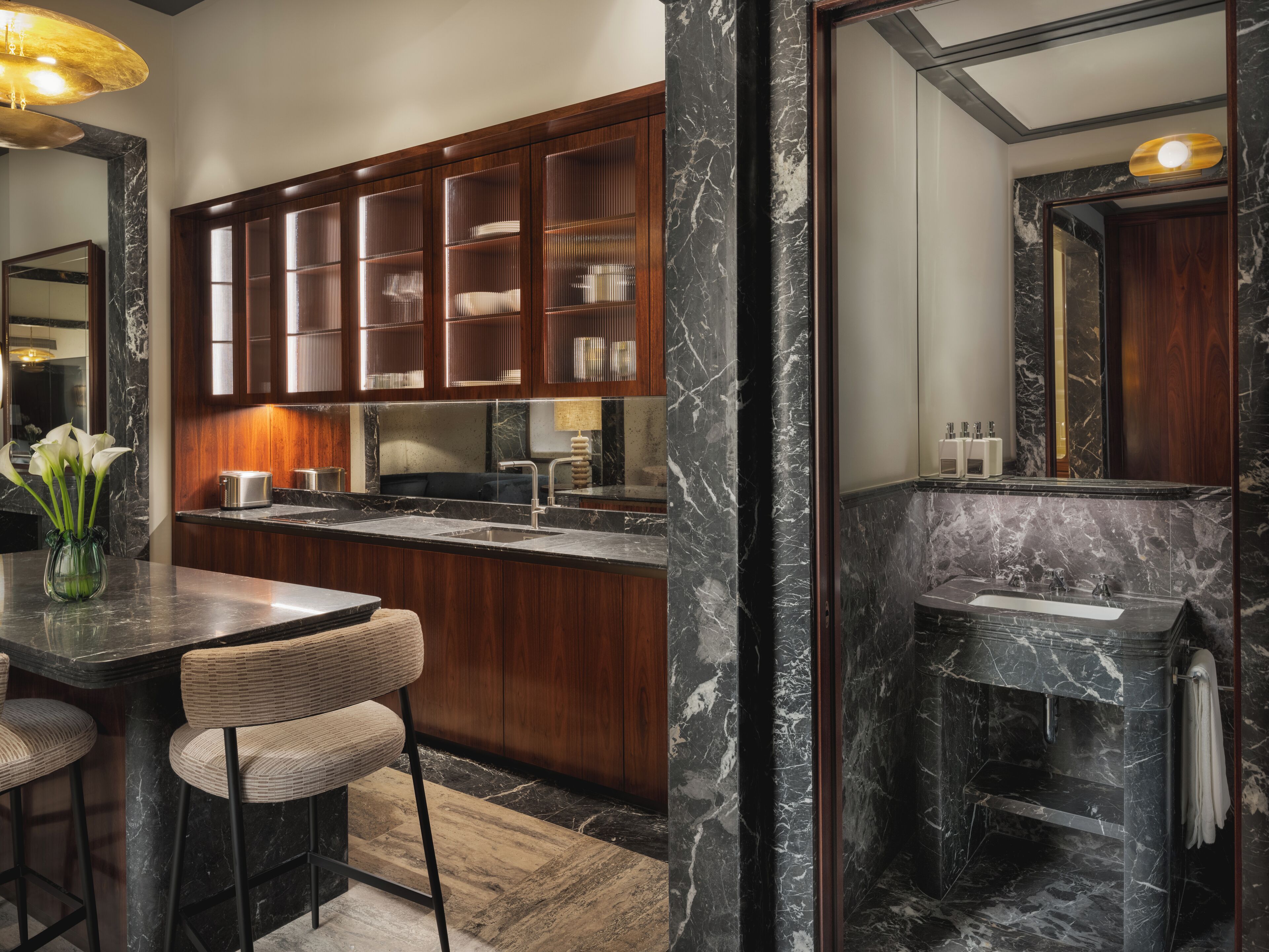 A modern kitchen with dark wood cabinets, a marble countertop, and a built-in island with bar stools.
